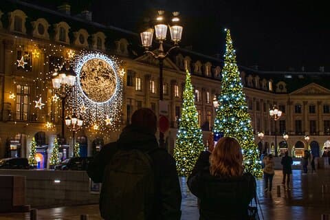 People taking photos of Christmas trees lit up at night