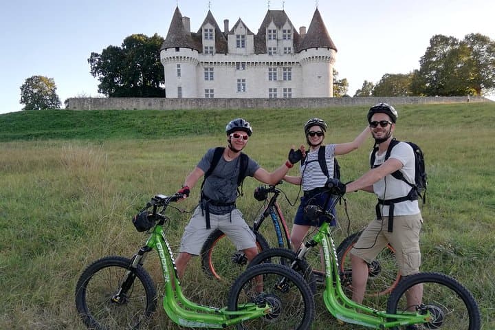 Group of young people on all-terrain electric scooters in front of the castle of Monbazillac