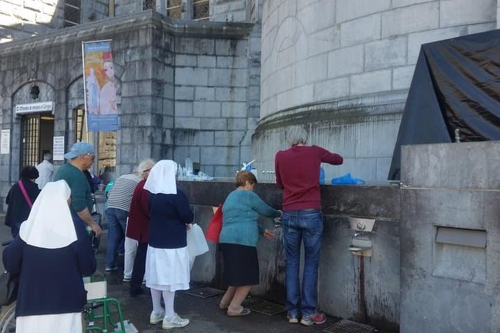 Fetching holy water near the grotto.