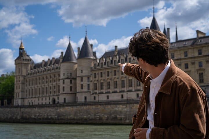 guy pointing at the Conciergerie, a medieval castle across the river