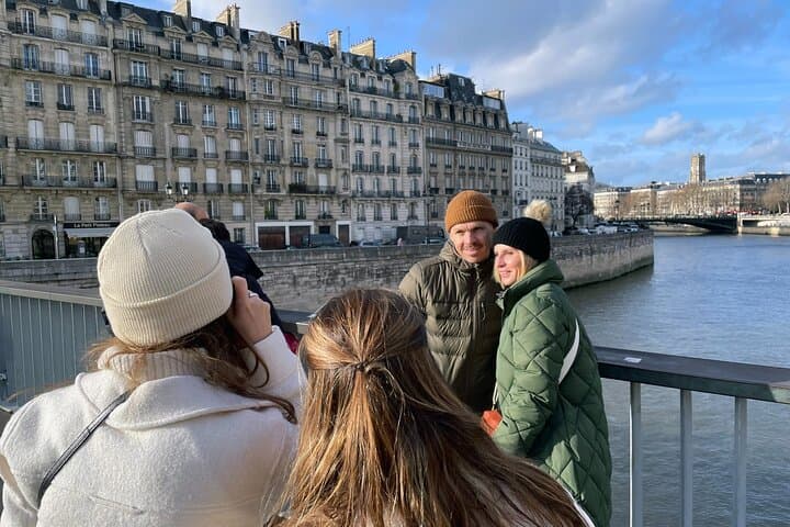 2 girls taking photos of a couple in front of a the river Seine
