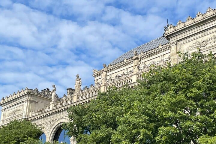 statues above a building and trees