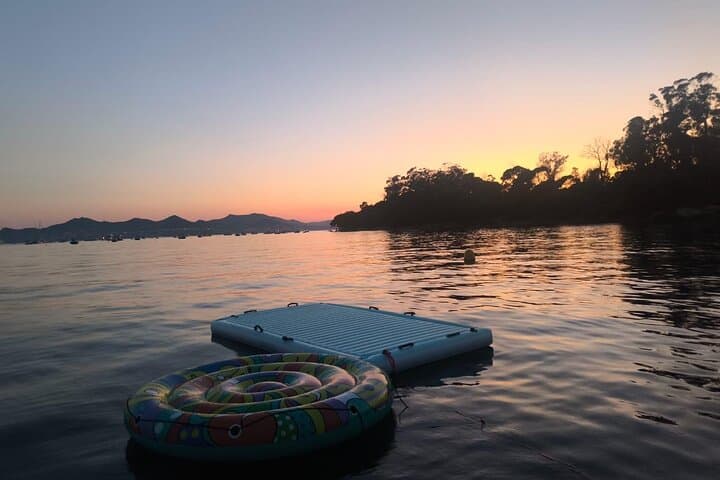 “Relaxing swim area with floating mat at sunset”