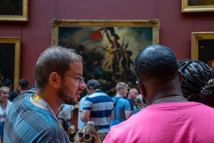 3 people talking in front of a painting